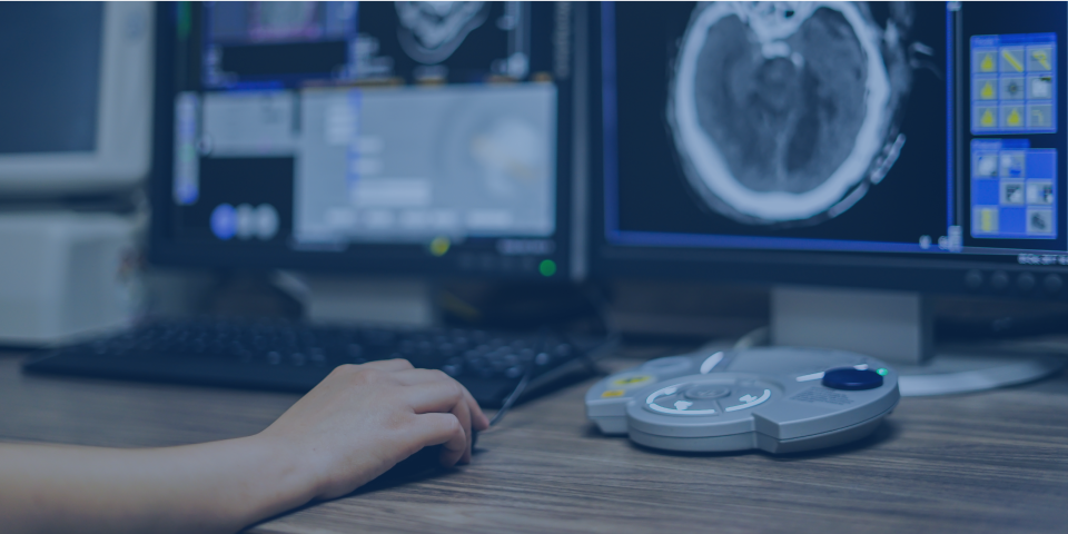 Radiology online reporting system showing brain scan on monitor.